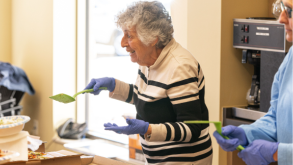 Lady serving pizza to seniors at Village Hall