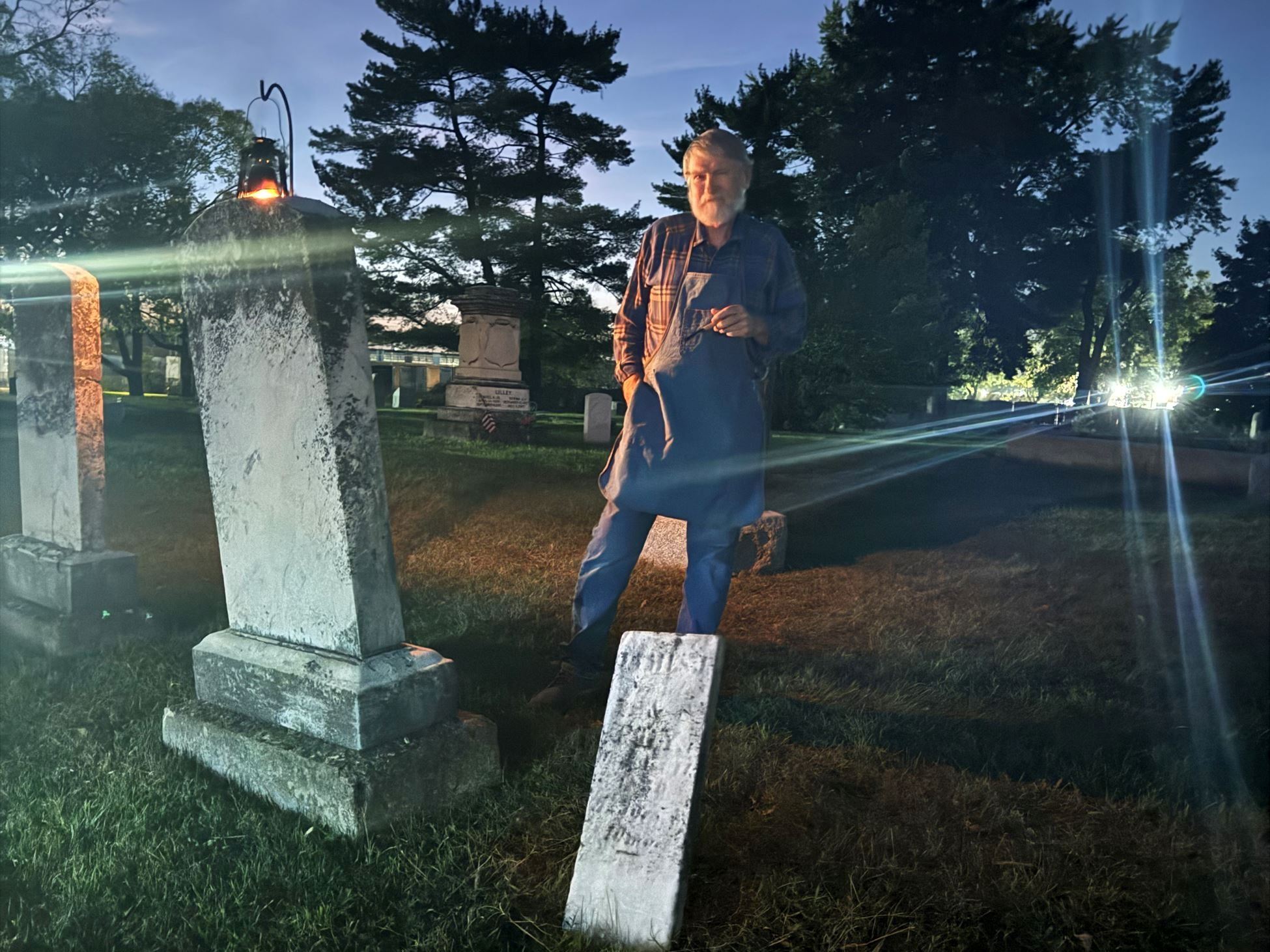 Man standing in cemetery at night.